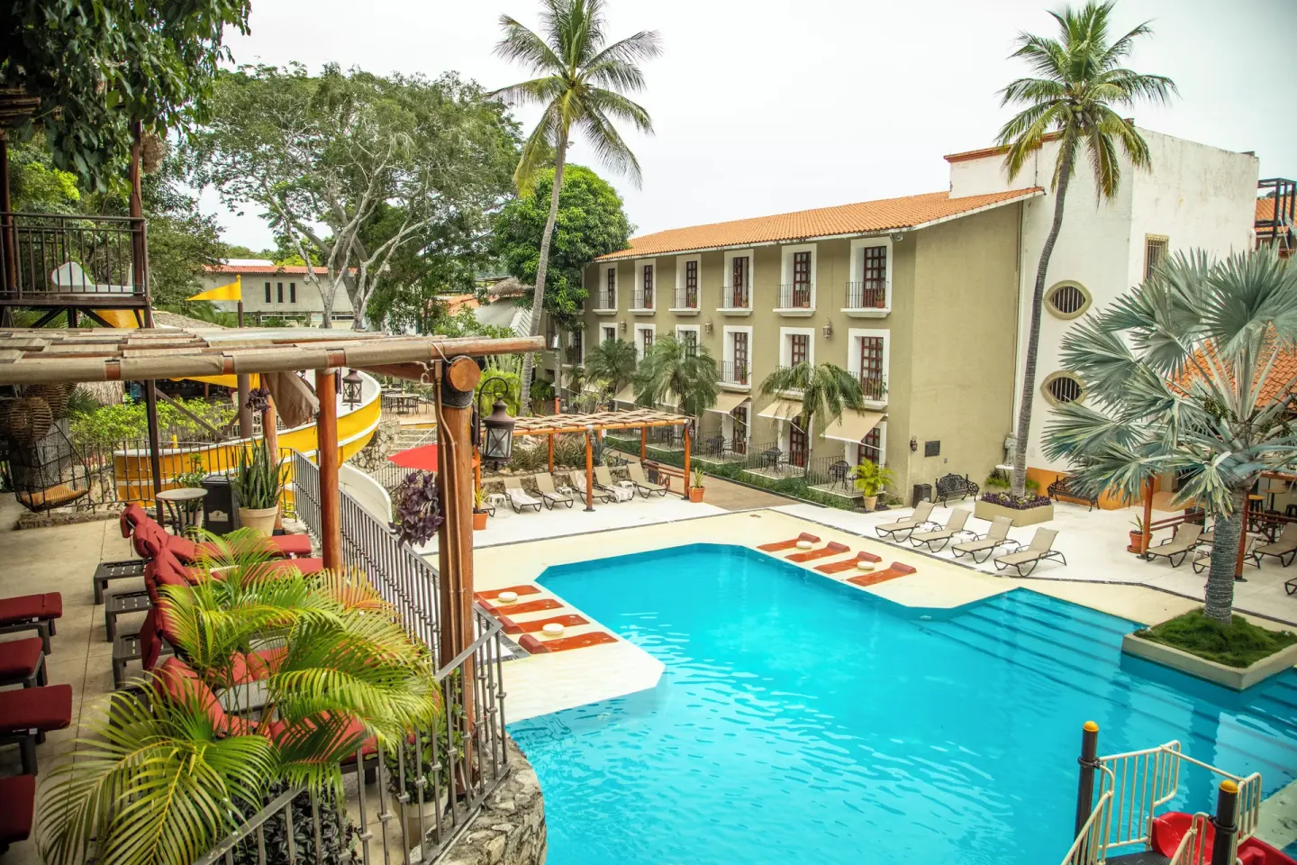 Main pool with loungers and palms at Binniguenda Huatulco & Beach Club.