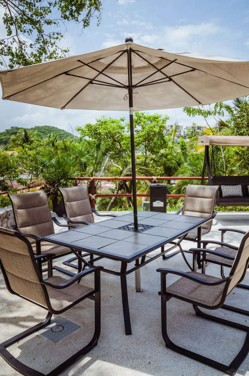 Outdoor patio table with umbrella and chairs at Binniguenda Huatulco & Beach Club.