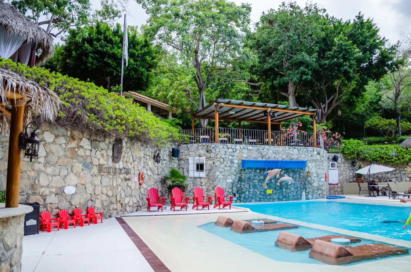Pool with red lounge chairs and stone walls at Binniguenda Huatulco & Beach Club.
