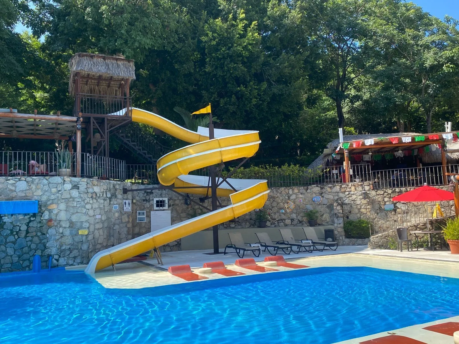 Pool with yellow waterslide at Binniguenda Huatulco & Beach Club.