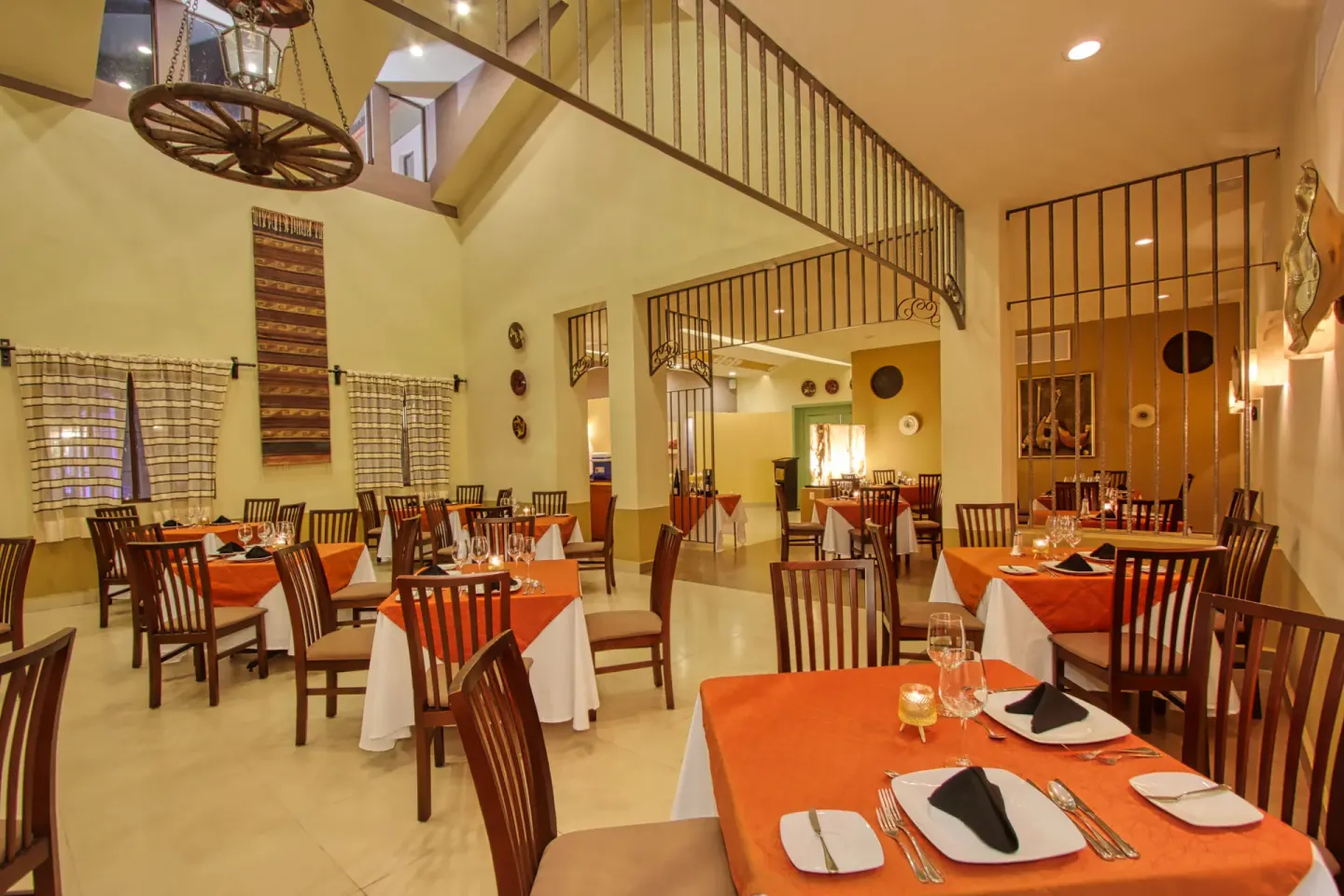 Warm indoor dining room with orange table linens at Binniguenda Huatulco & Beach Club.