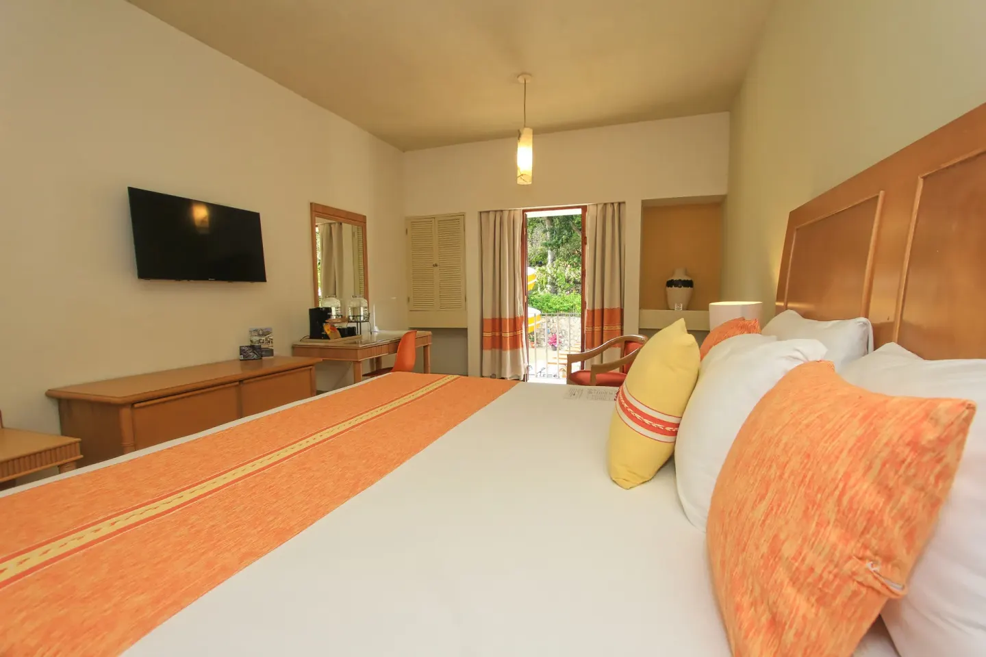 Standard Room bed with orange accents and balcony doors at Binniguenda Huatulco & Beach Club.