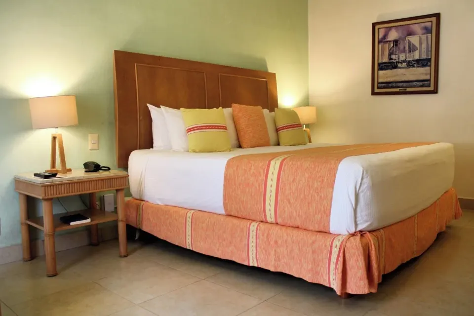 Standard Room king bed with bedside lamp and framed artwork at Binniguenda Huatulco & Beach Club.