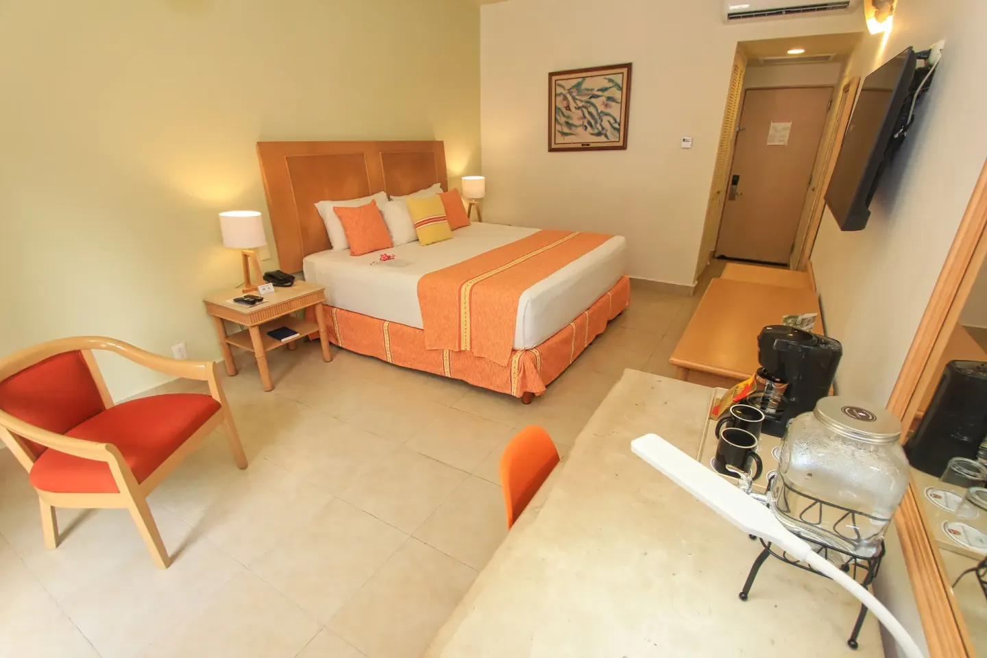 Standard Room king bed with seating, TV, desk, and drink station at Binniguenda Huatulco & Beach Club.