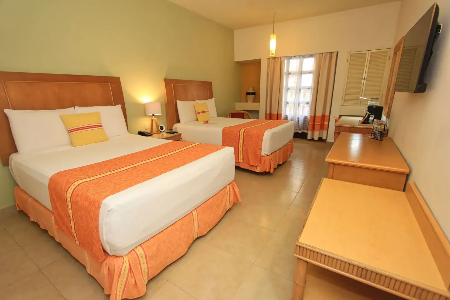 Standard Room with two beds, orange runners, TV, and desk at Binniguenda Huatulco & Beach Club.