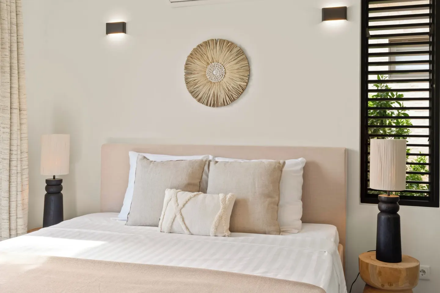 Neutral guest room bed with woven wall art at Blue Bay Curacao Golf & Beach Resort.