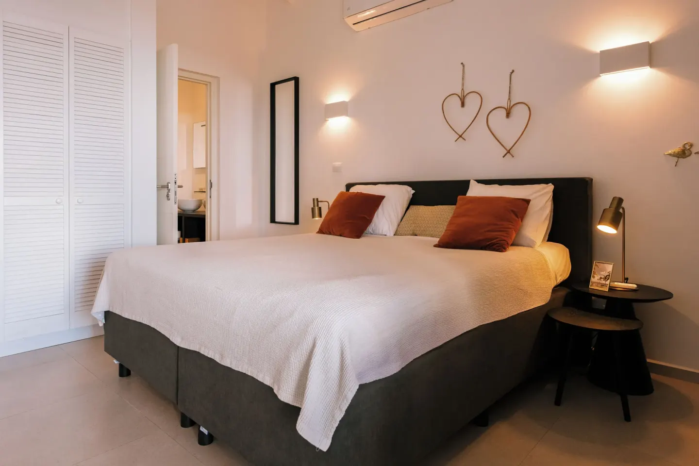 Guest room with king bed, white closet doors, and heart wall decor at Blue Bay Curacao Golf & Beach Resort.