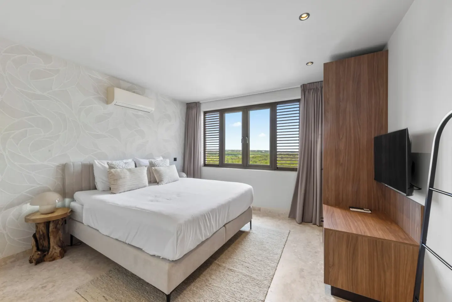 Guest room king bed with landscape-facing windows at Blue Bay Curacao Golf & Beach Resort.