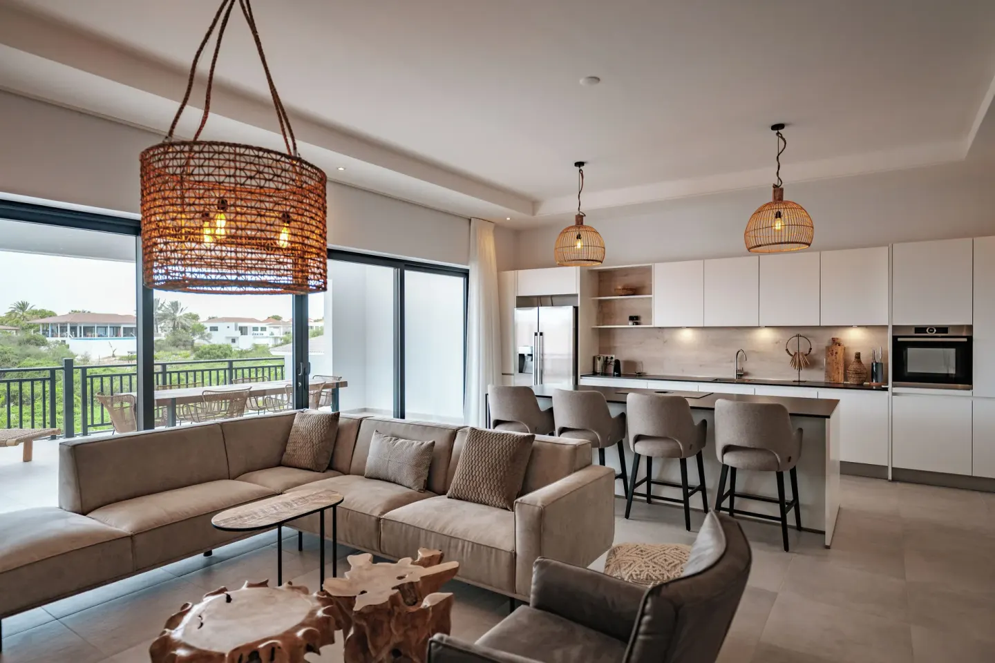 Living room and white kitchen with balcony view at Blue Bay Curacao Golf & Beach Resort.