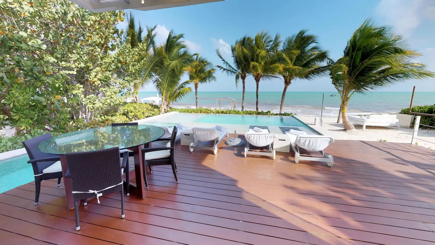 Beachfront deck with pool, loungers, and palms at Blue Diamond Luxury Boutique.