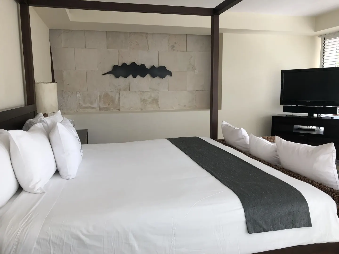 Canopy bed, pillows, wall art, and TV in a guest room at Blue Diamond Luxury Boutique.