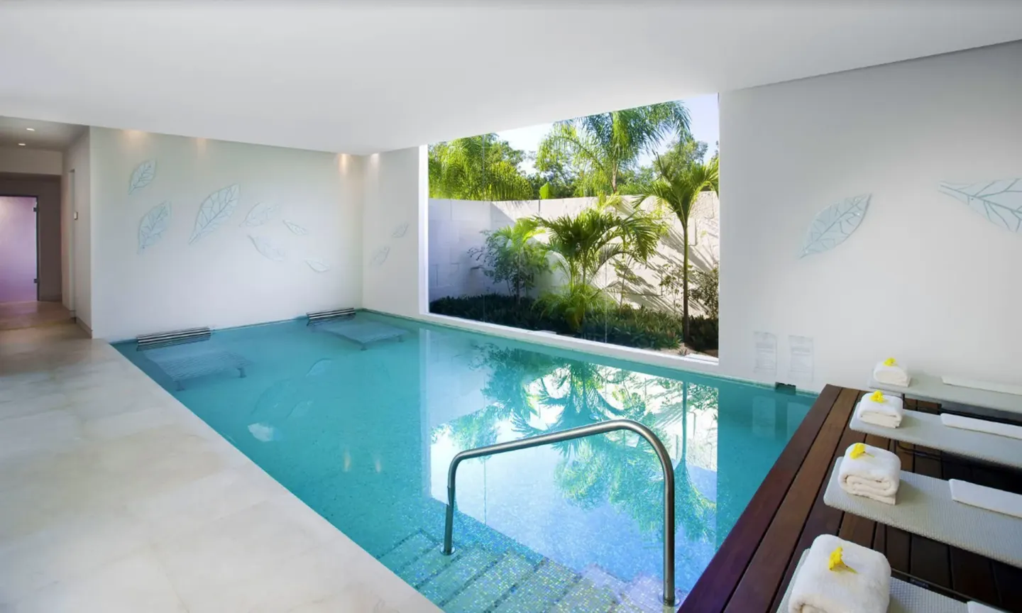 Indoor plunge pool at Blue Diamond Luxury Boutique with loungers, steps, and a garden opening.