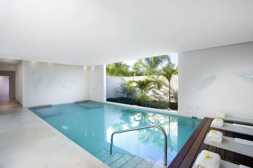 Indoor spa pool with loungers and palm views at Blue Diamond Luxury Boutique.