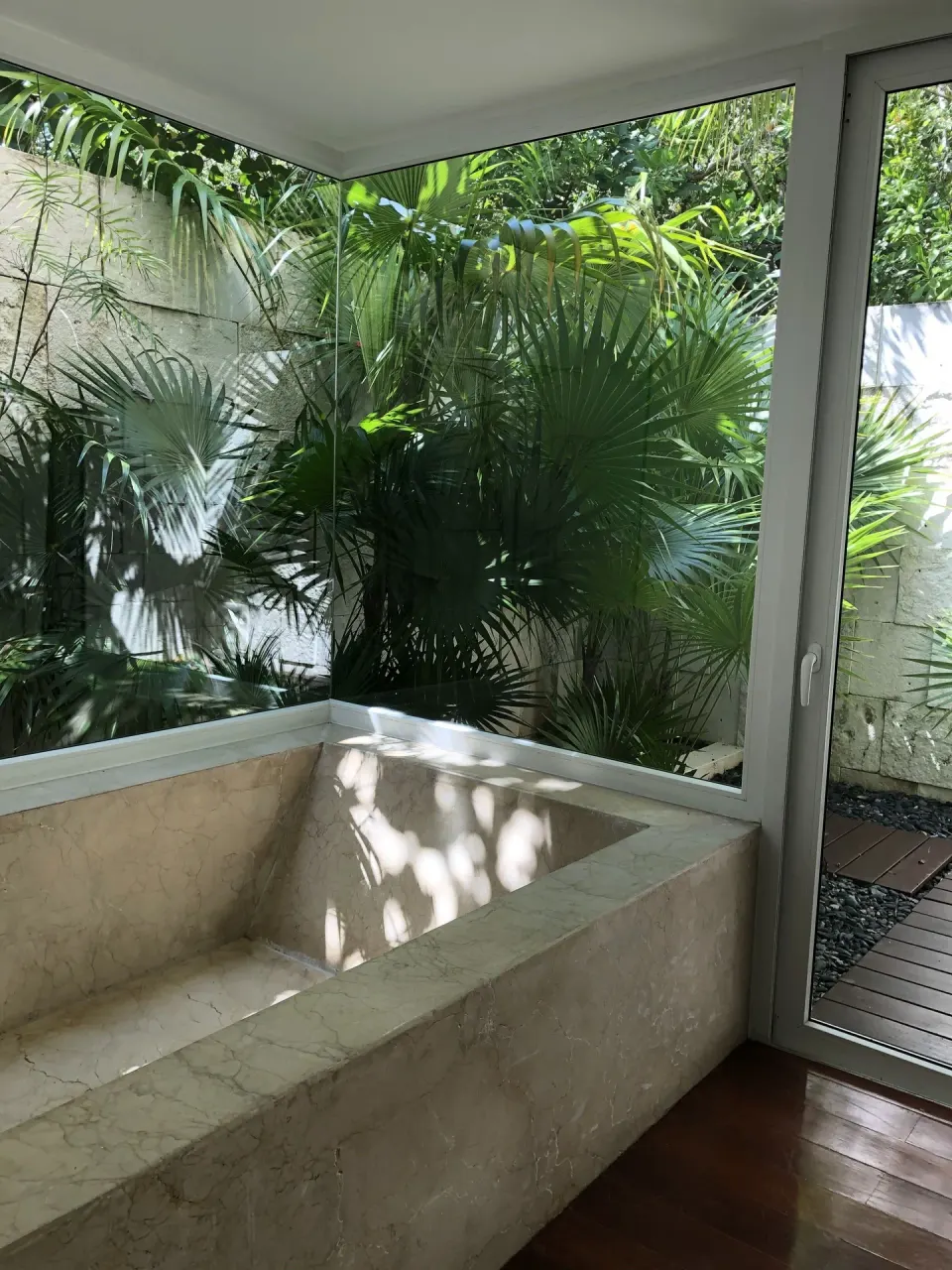 Empty marble tub by tropical garden windows at Blue Diamond Luxury Boutique.