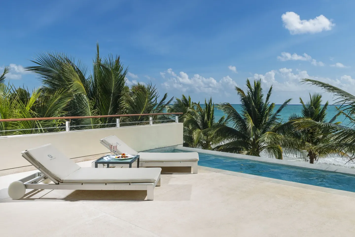 Ocean-view terrace pool at Blue Diamond Luxury Boutique with white loungers and palm trees.