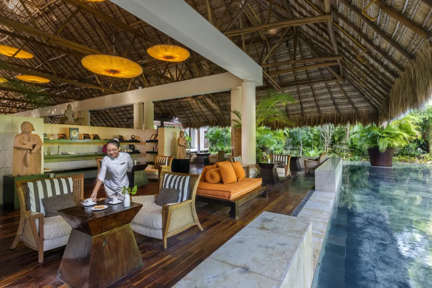 Open-air lounge with thatched roof and reflecting water at Blue Diamond Luxury Boutique.