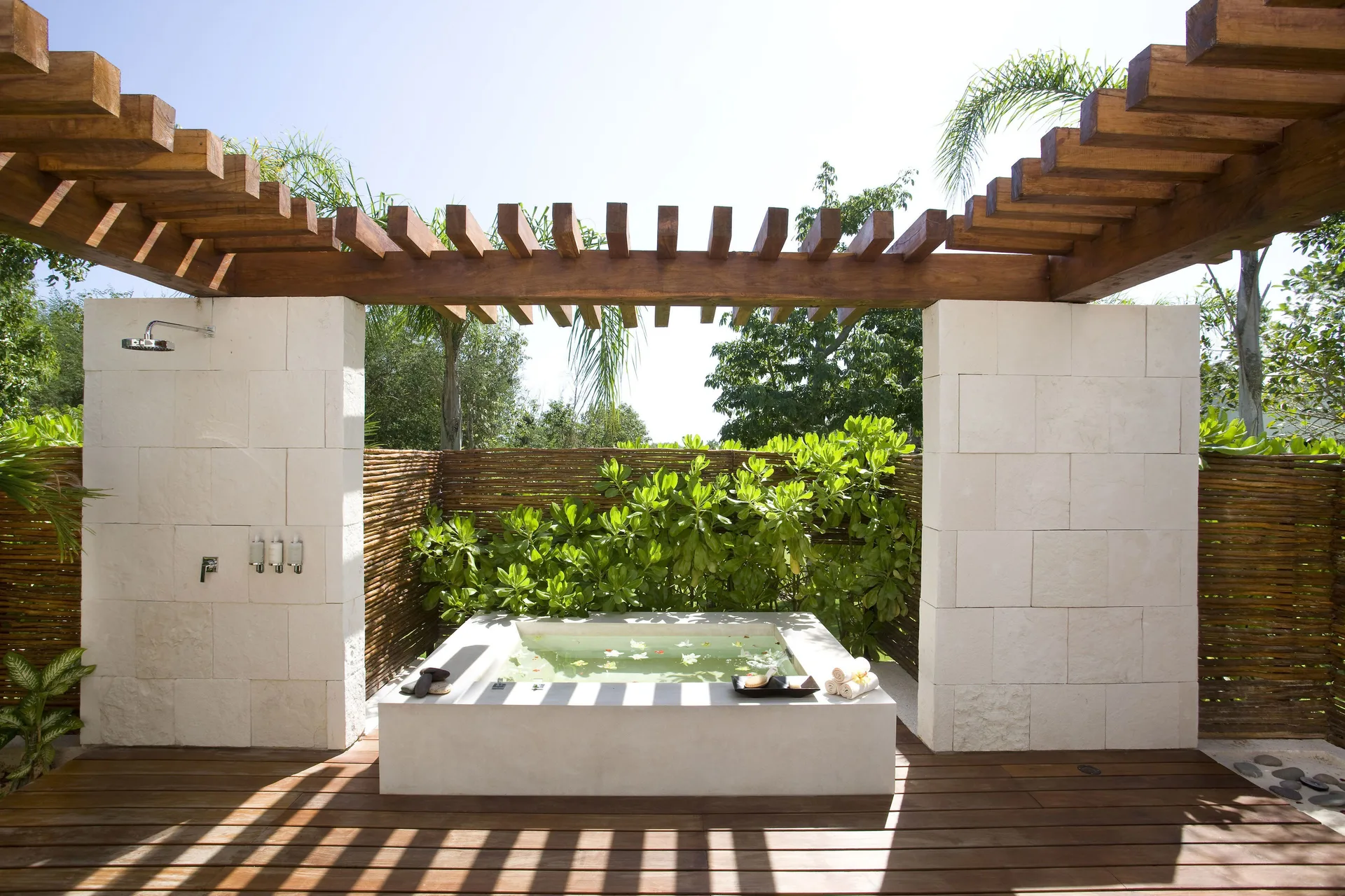 Outdoor soaking tub and shower under a pergola at Blue Diamond Luxury Boutique.