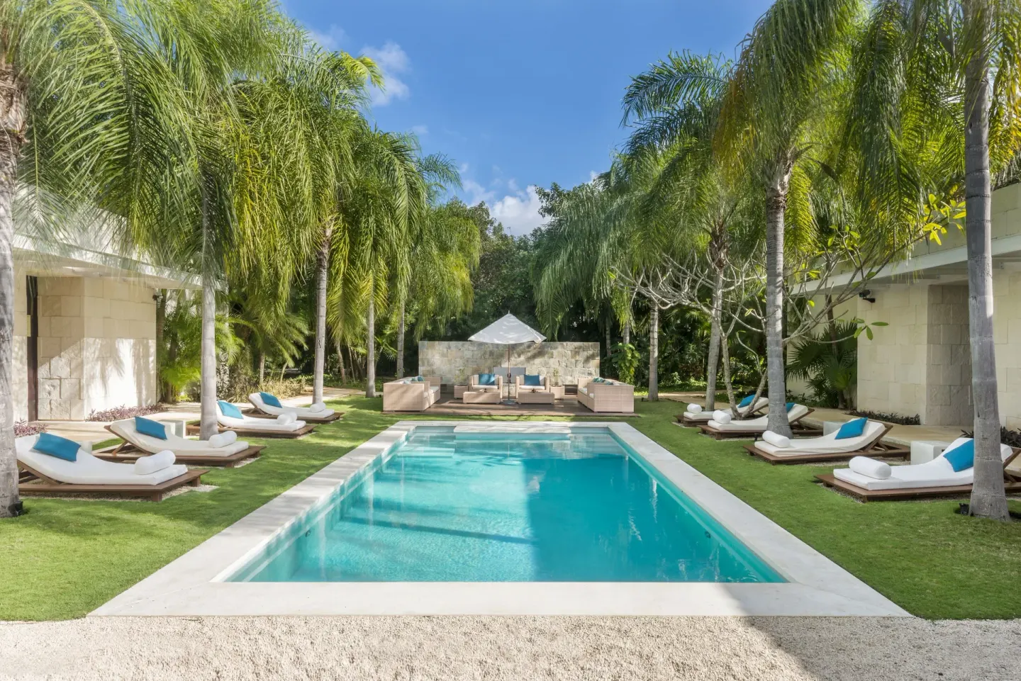 Palm garden pool at Blue Diamond Luxury Boutique with turquoise pillows on surrounding loungers.