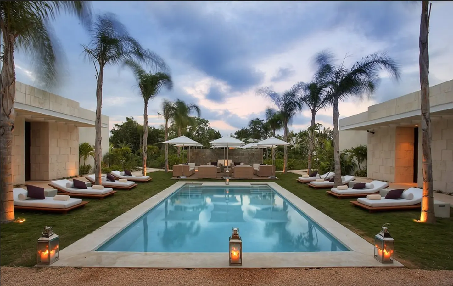Palm-lined private pool courtyard at Blue Diamond Luxury Boutique with loungers and lanterns at dusk.