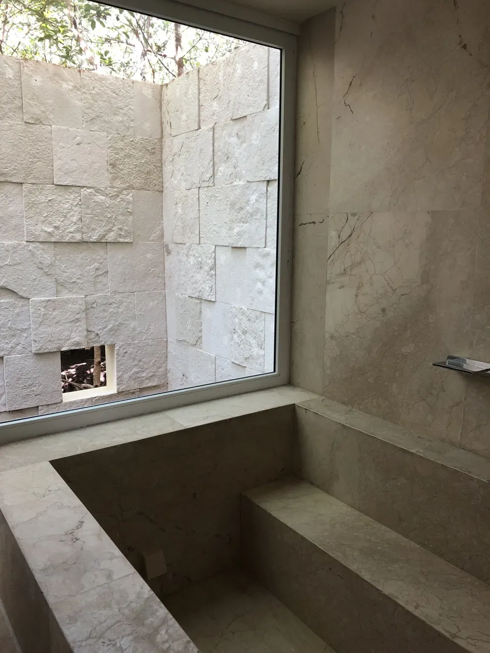 Sunken stone bathtub facing a private wall at Blue Diamond Luxury Boutique.