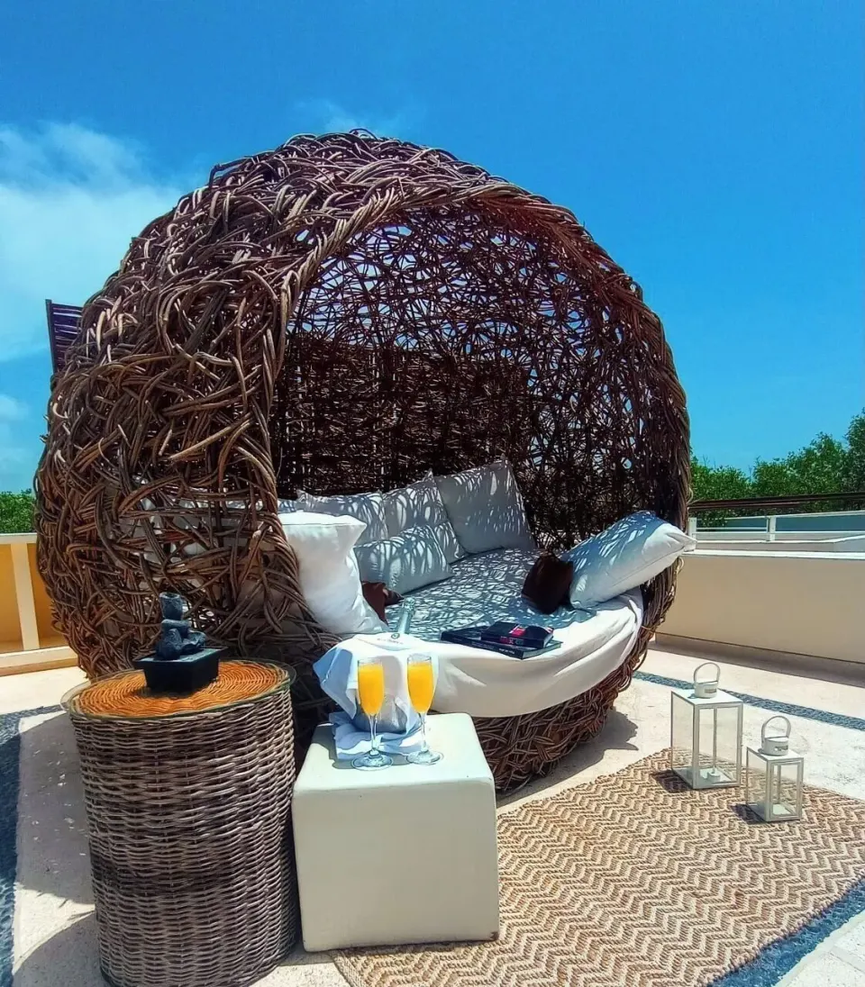 Woven outdoor daybed with pillows on a terrace at Blue Diamond Luxury Boutique.