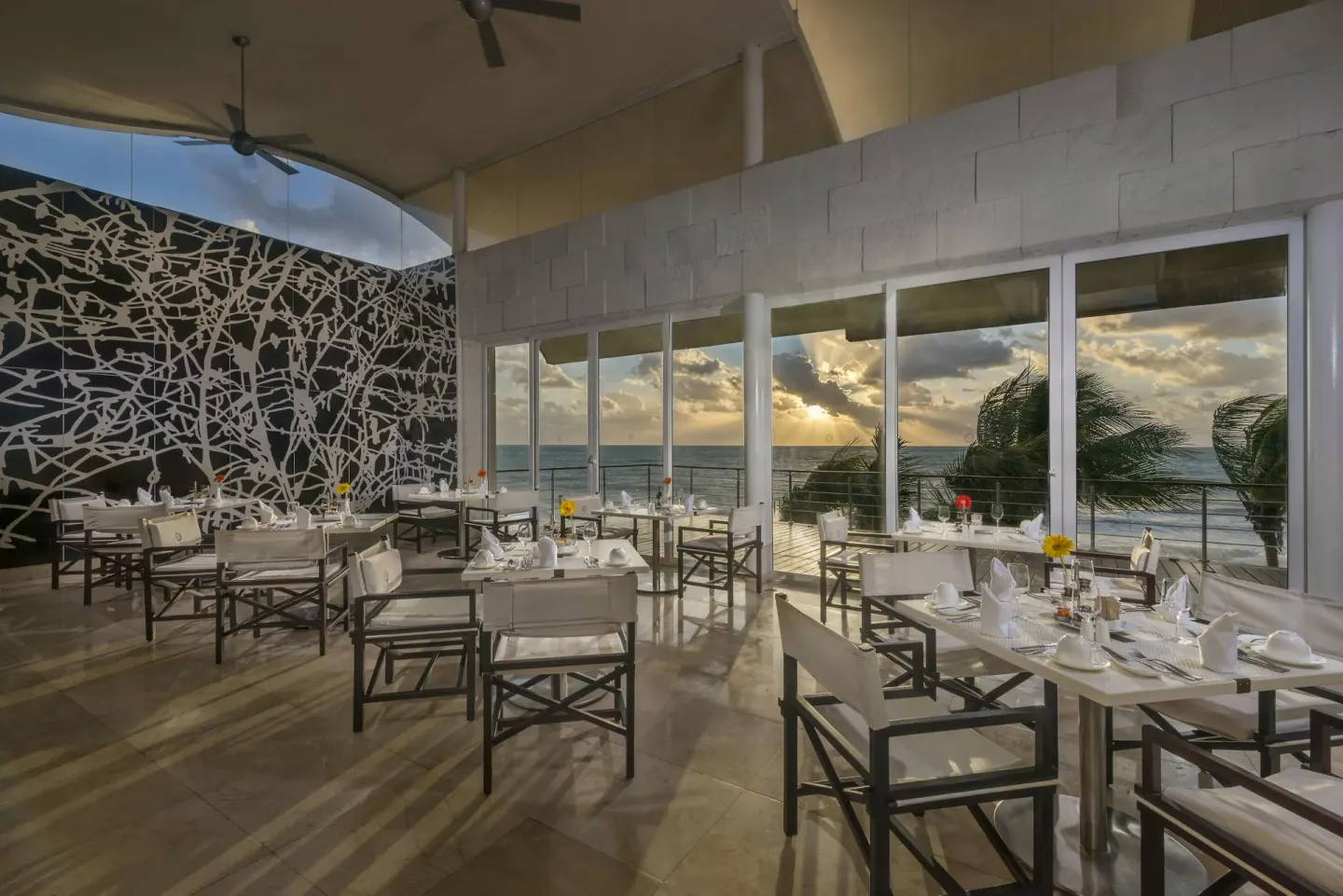 Oceanfront dining room with white chairs and sunset windows at Blue Diamond Luxury Boutique.