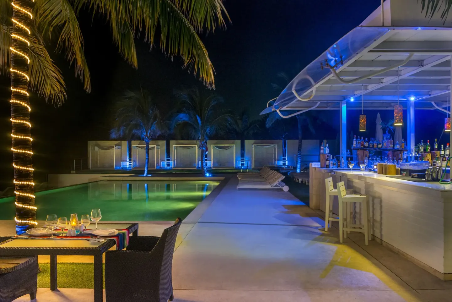 Poolside bar and lit swimming pool at night at Blue Diamond Luxury Boutique.