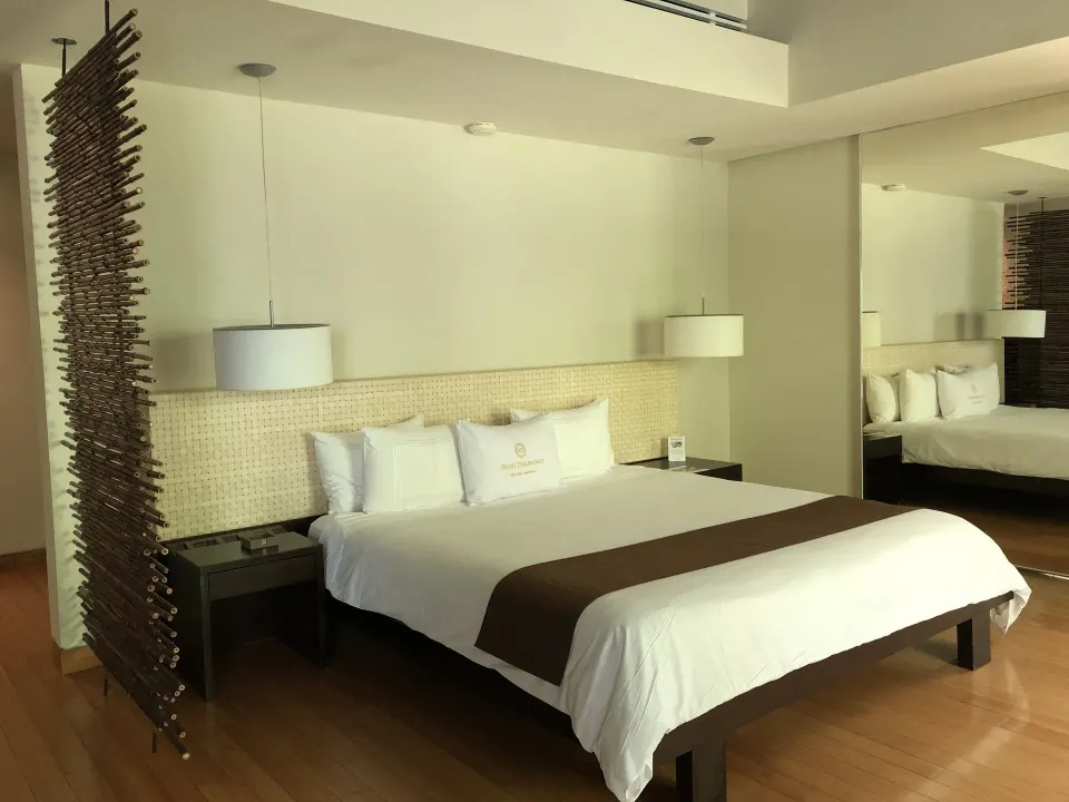 Junior Suite king bed at Blue Diamond Luxury Boutique with pendant lamps and mirrored wall.