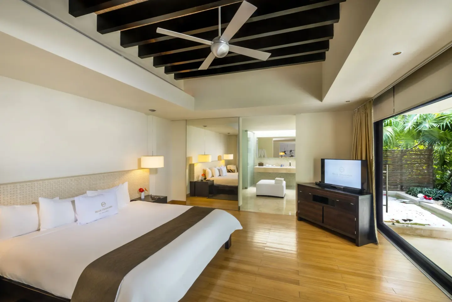 Junior Suite king bed at Blue Diamond Luxury Boutique with TV, patio glass, and bathroom beyond.