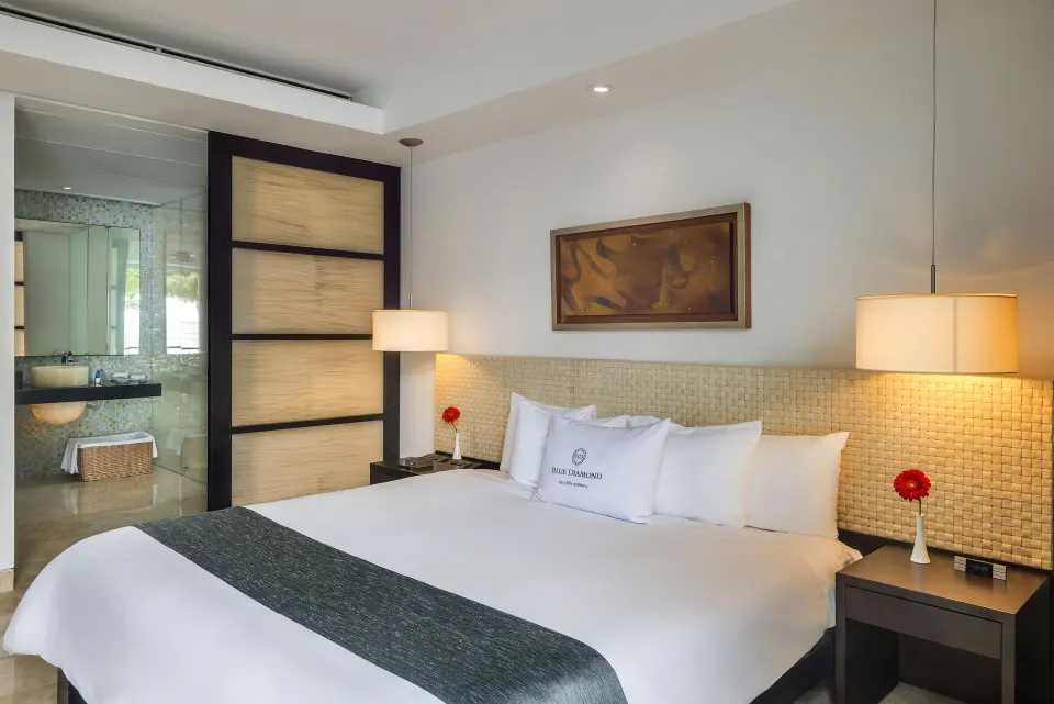 Patio Diamond Suite king bed with bedside lamps and open bathroom at Blue Diamond Luxury Boutique.