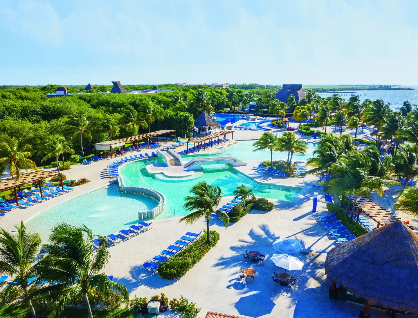 Aerial view of pools, palms, loungers and shoreline at BlueBay Grand Esmeralda.