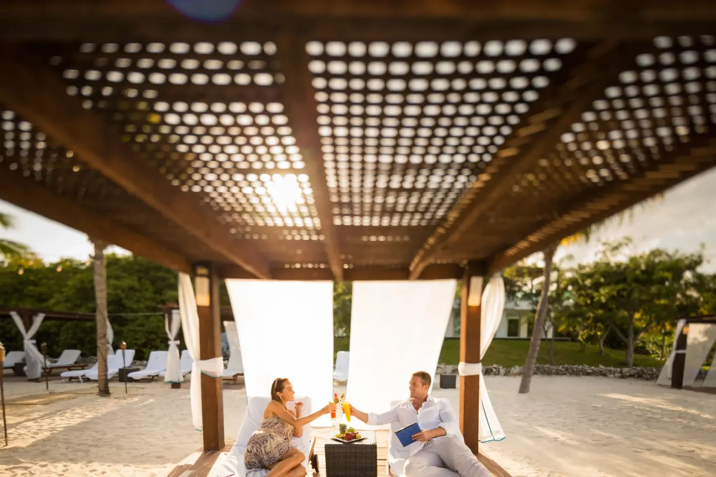 Beach cabana with guests toasting drinks at BlueBay Grand Esmeralda.