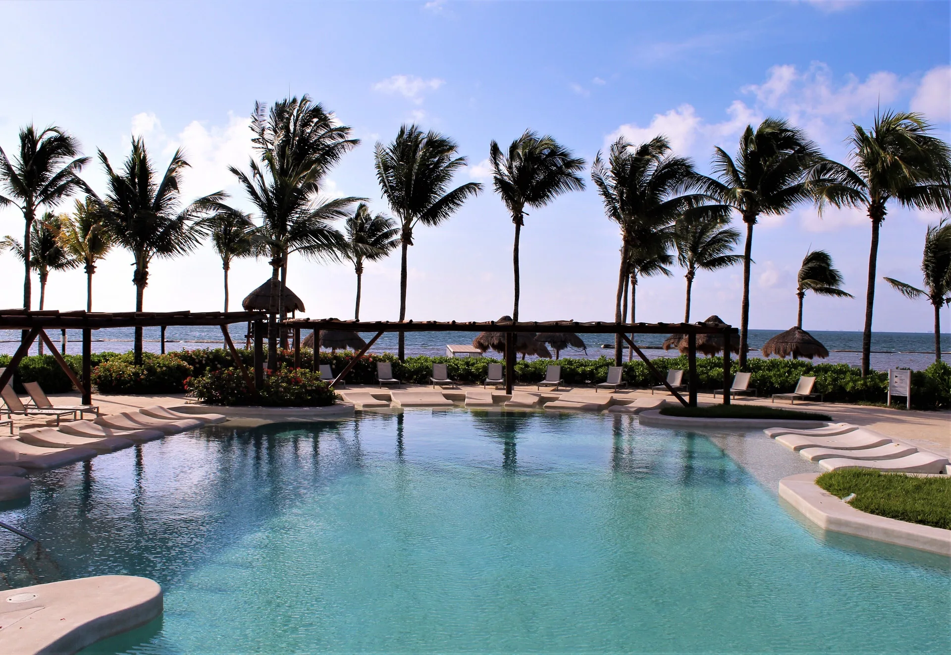 Beachfront pool framed by palms and ocean views at BlueBay Grand Esmeralda.