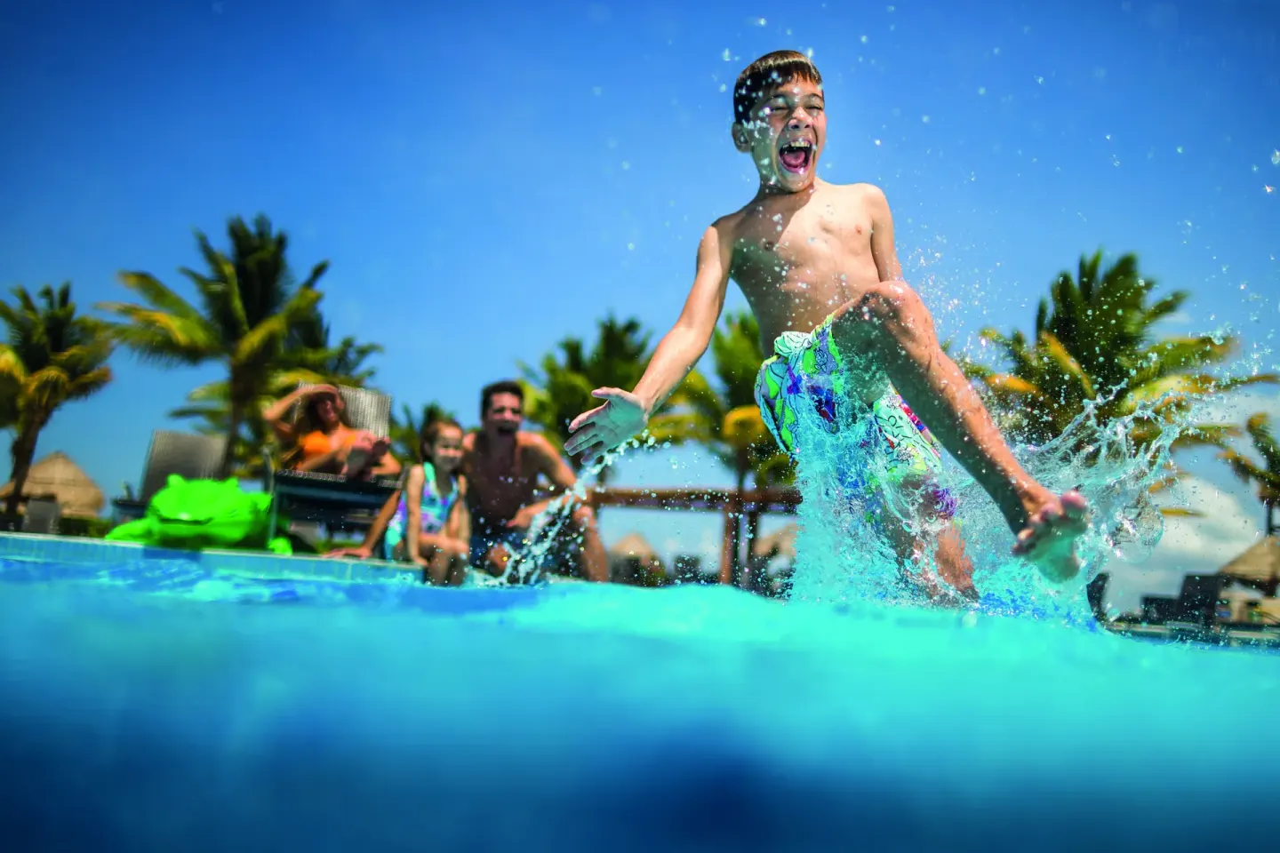 Child jumping and splashing in the pool at BlueBay Grand Esmeralda.