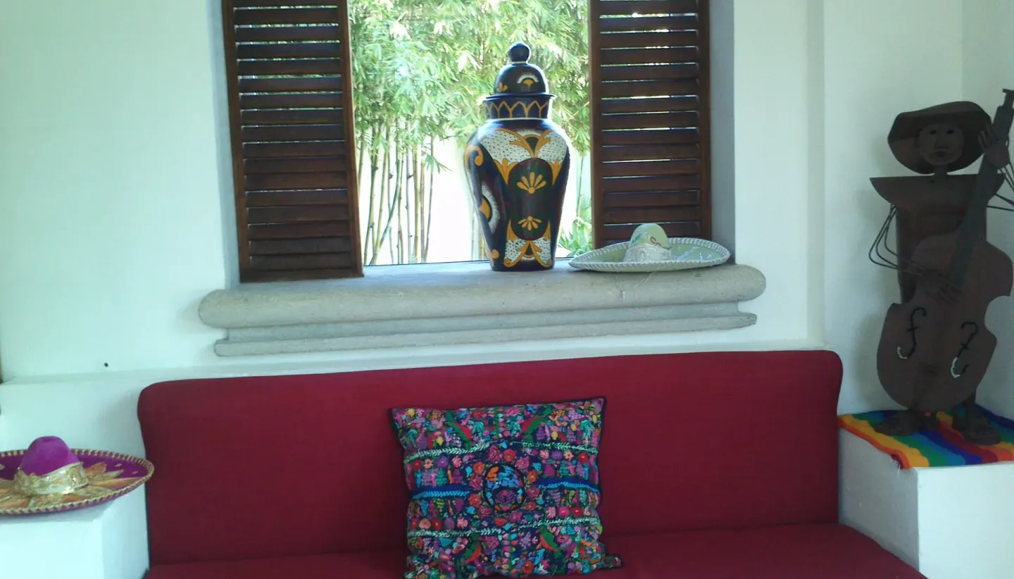 Decorative lounge nook with red bench and Mexican-inspired art at BlueBay Grand Esmeralda.
