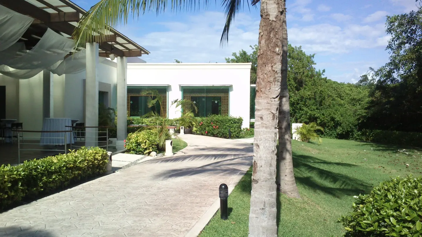 Resort walkway with palms, lawns, and terrace entrance at BlueBay Grand Esmeralda.