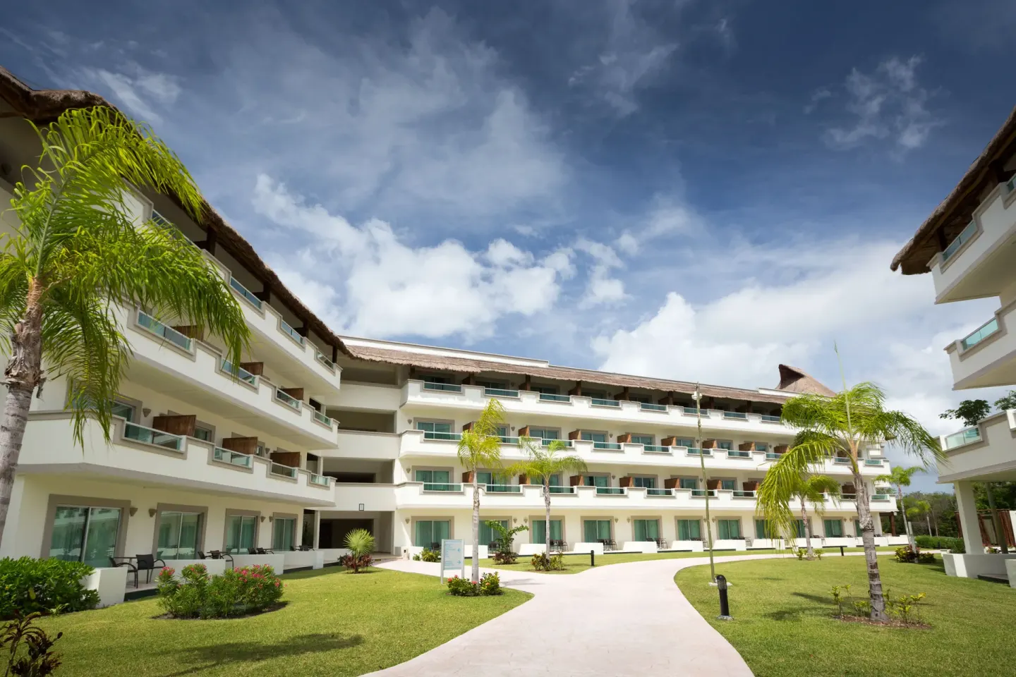 Guestroom building courtyard with balconies and palm trees at BlueBay Grand Esmeralda.