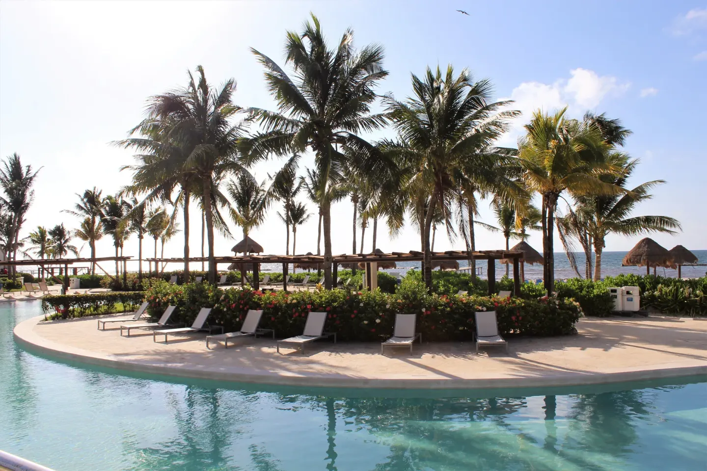 Palm-lined pool with loungers and ocean beyond at BlueBay Grand Esmeralda.