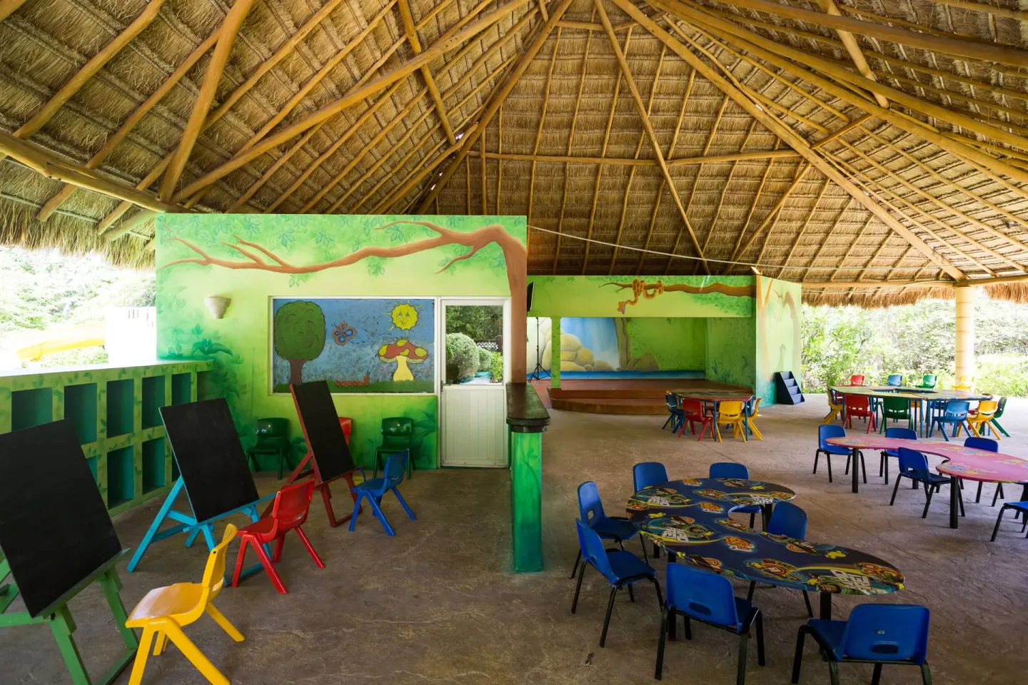 Thatched kids club with activity tables and chalkboards at BlueBay Grand Esmeralda.