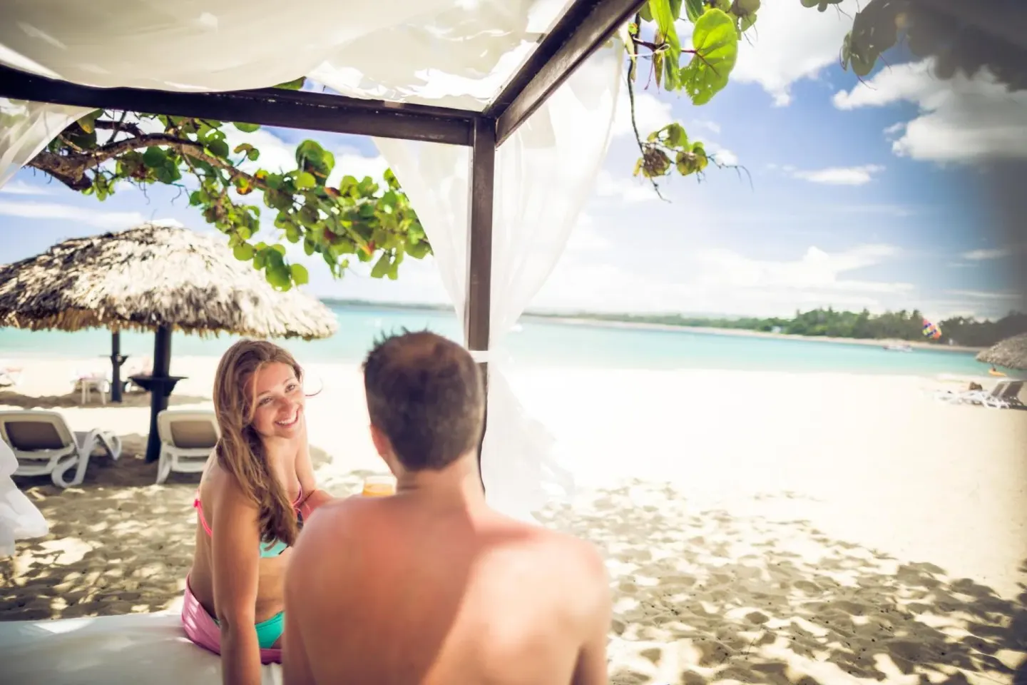 Couple relaxing in a shaded beach cabana at BlueBay Villas Doradas.