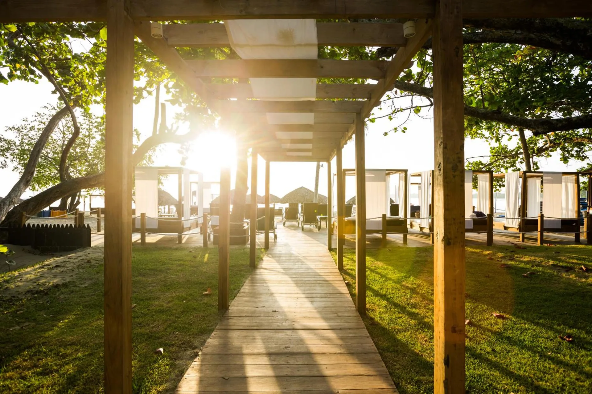 Beach walkway with cabanas in golden light at BlueBay Villas Doradas.
