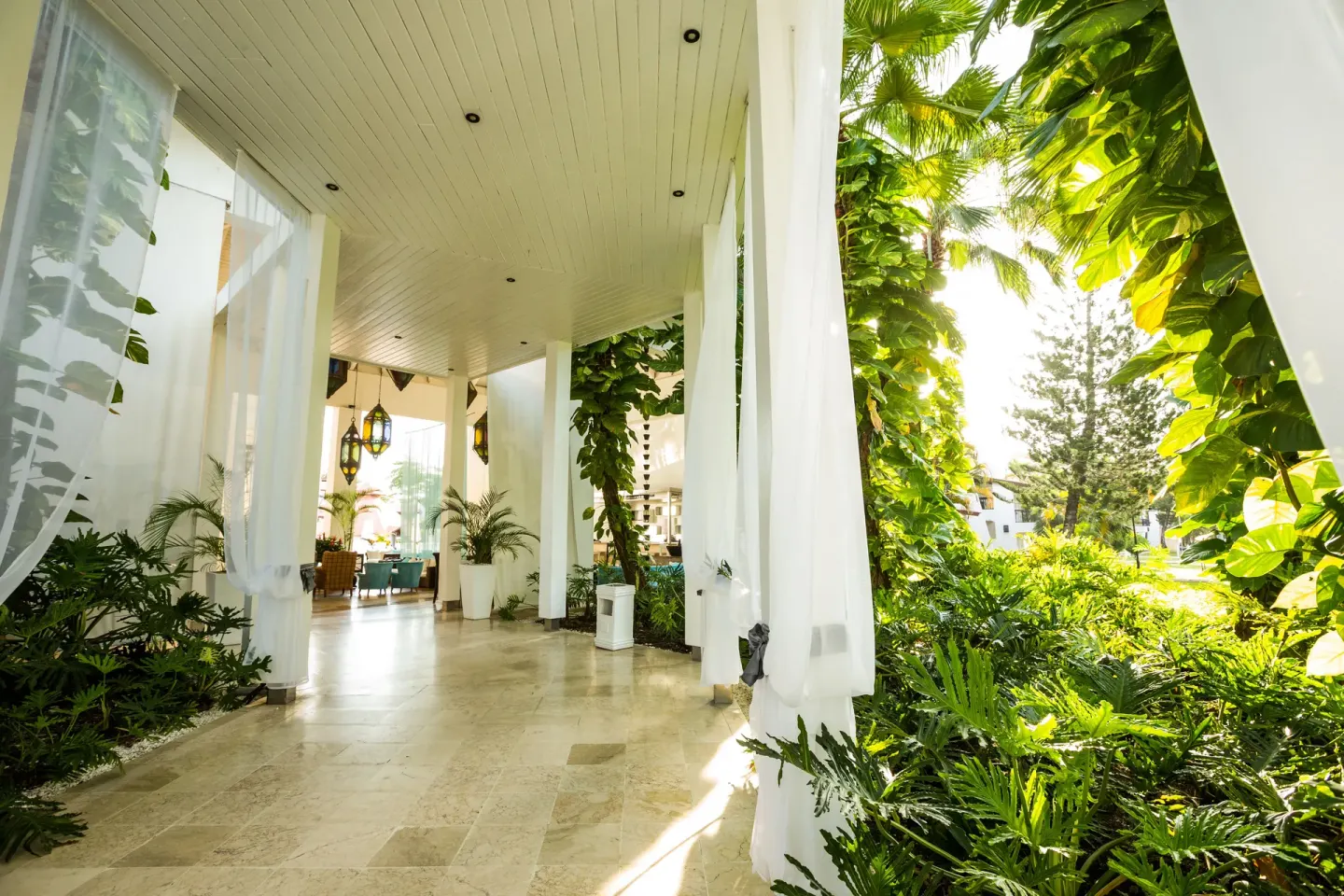 Covered garden walkway with white curtains at BlueBay Villas Doradas.
