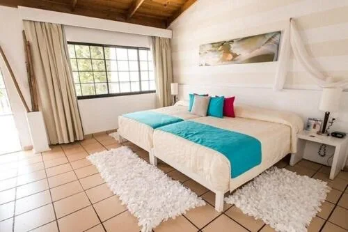 Guest room with two double beds and turquoise accents at BlueBay Villas Doradas.