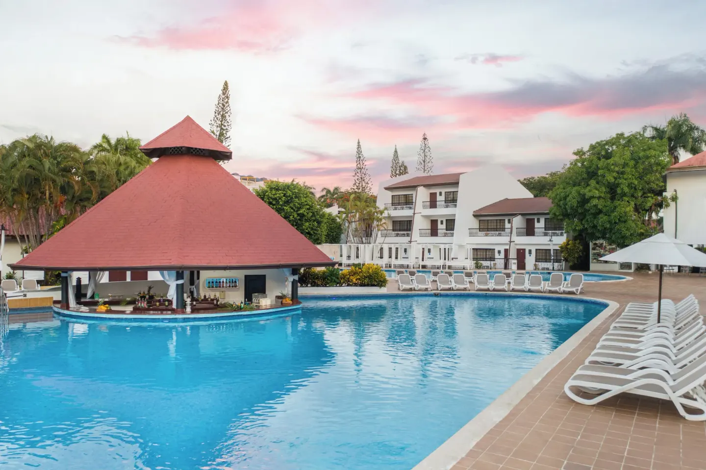 Curved pool with swim-up bar and loungers at BlueBay Villas Doradas.