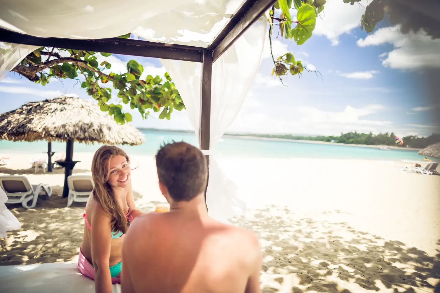 Couple relaxing on a shaded beach bed at BlueBay Villas Doradas.
