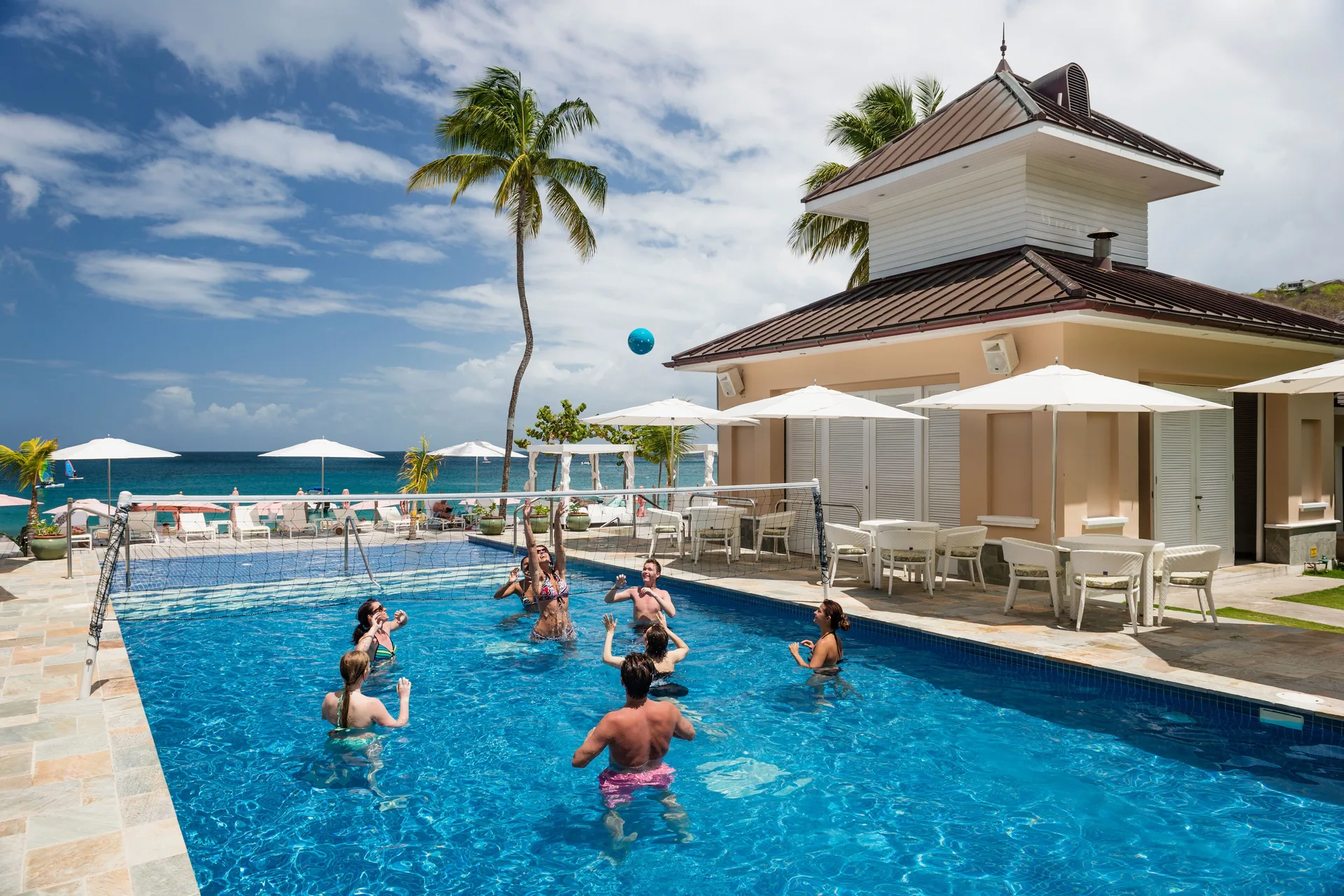 Guests playing volleyball in a beachfront pool at BodyHoliday.