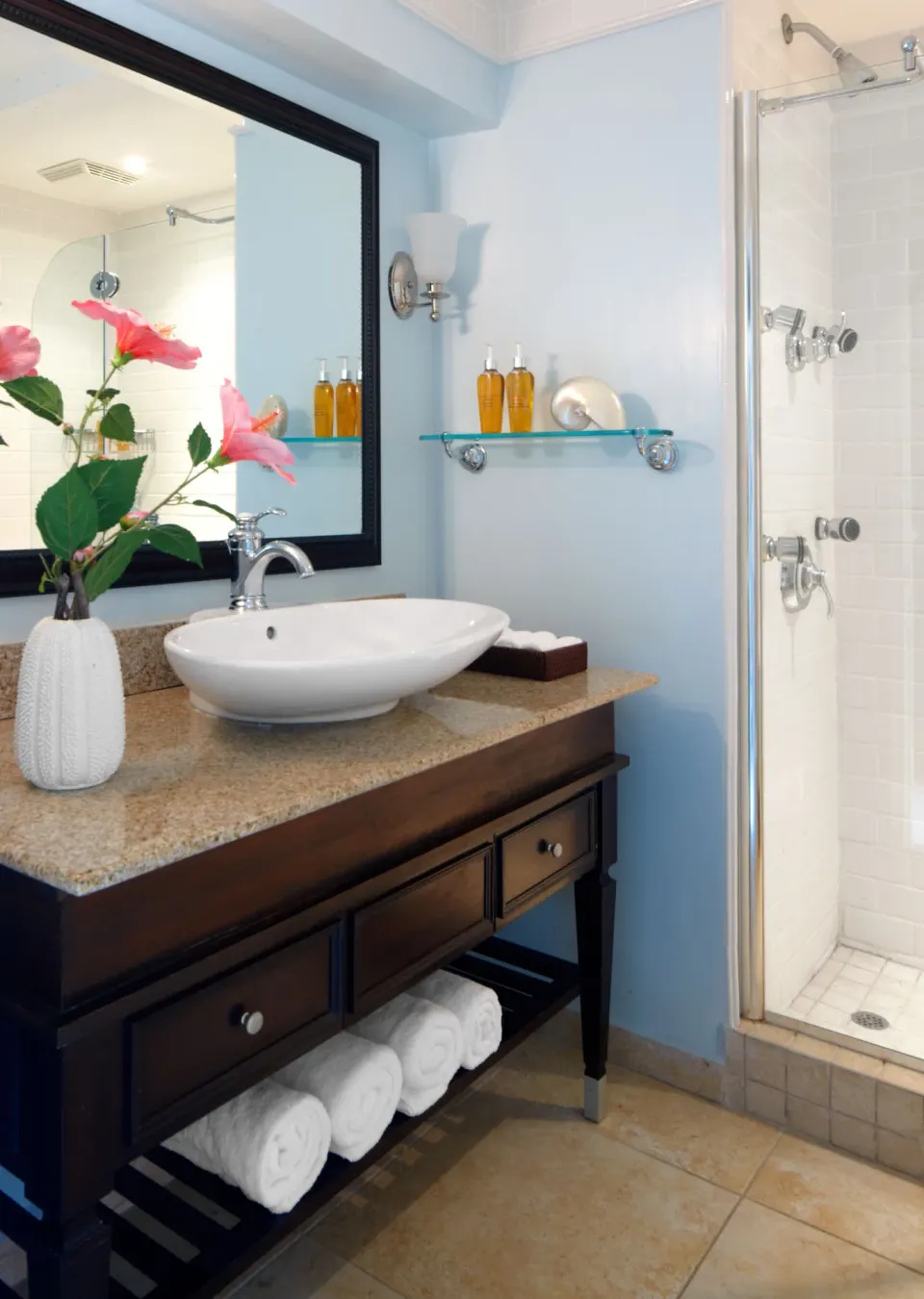 BodyHoliday bathroom with a vessel sink, shower, mirror, towels, and bath amenities.