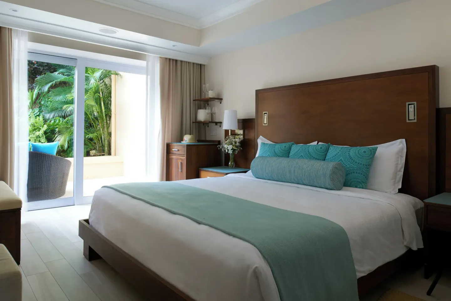 King-bed guest room at BodyHoliday opening to a patio with tropical plants.