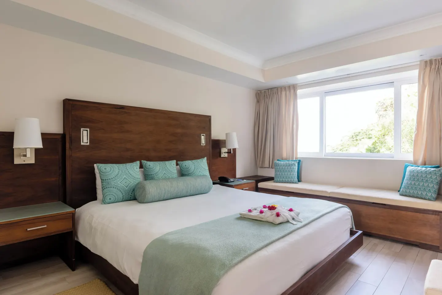 King-bed guest room at BodyHoliday with wooden headboard and window bench.