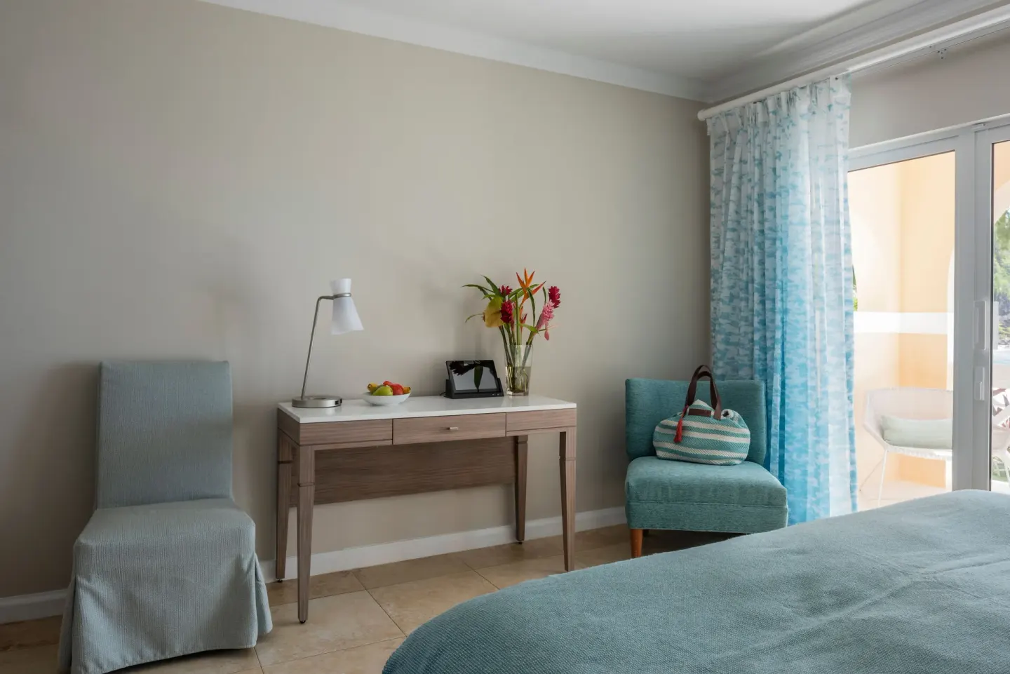 Guest room sitting area with desk, flowers, chairs, and balcony doors at BodyHoliday.